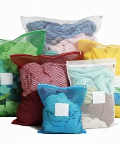 Farverige vaskenet uden lukkemekanisme i grøn, rød, gul og blå med hvide skrivemærkater til organisering af vasketøj